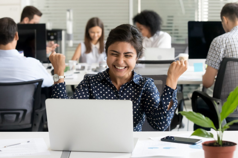 A person looking at her laptop with excitement over good news