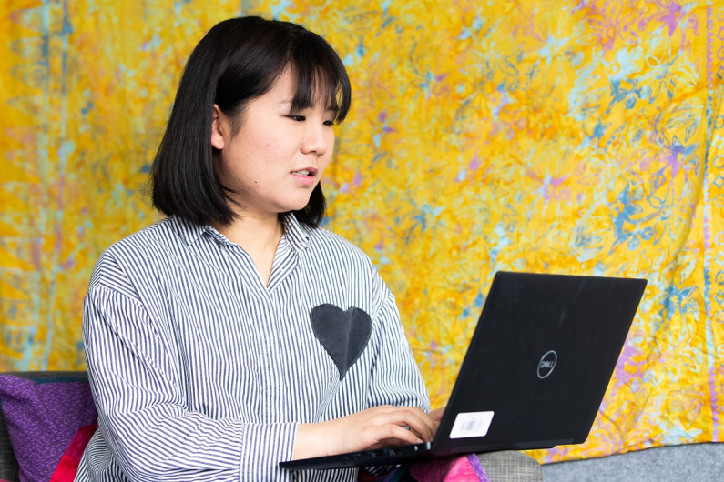 A person sits on a sofa using a laptop.