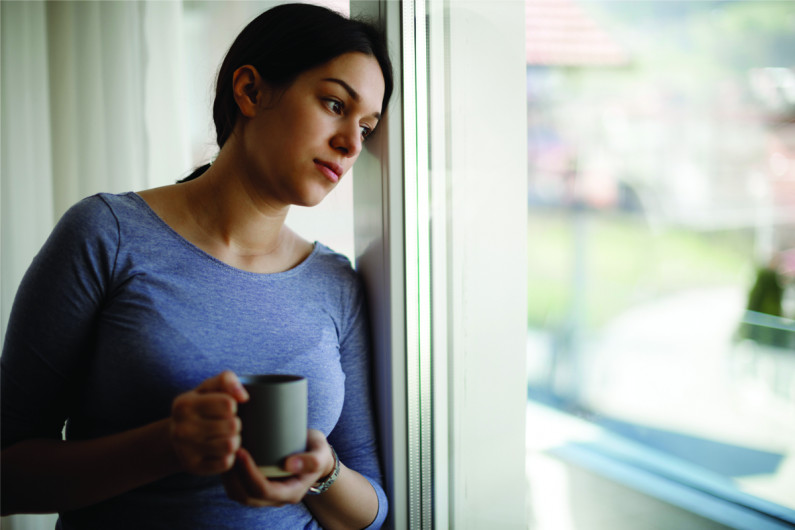 Sad young woman looking out window
