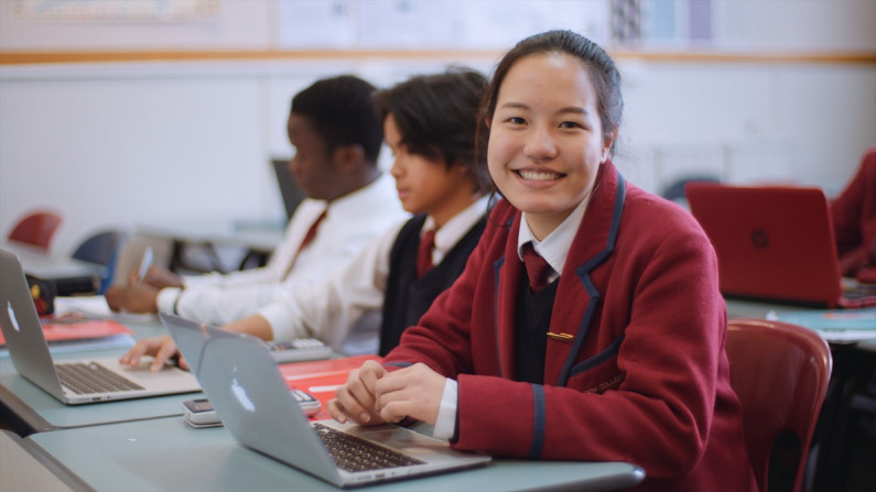 School learner sitting at desk with laptop