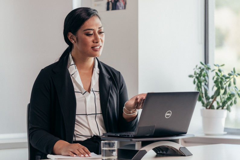 Woman negotiating looking into a laptop with her hand up 