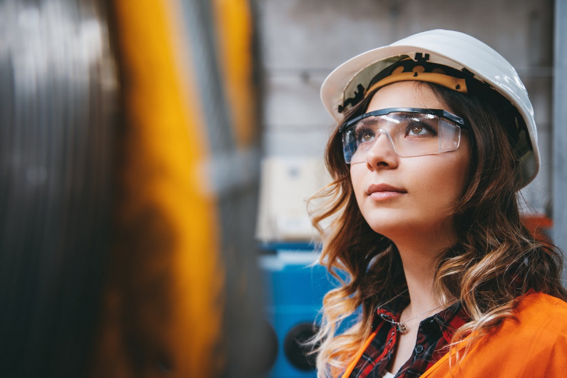 A young engineer testing wire resistance in a factory warehouse.