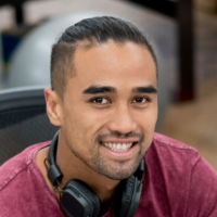 Young man smiling at camera with headphones on his neck.