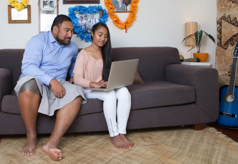 father and daughter look at laptop