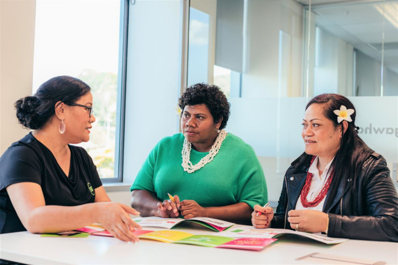 A Pacific career consultant and two Pacific Work Connect (PWC) participants sit at a table with PWC resources 