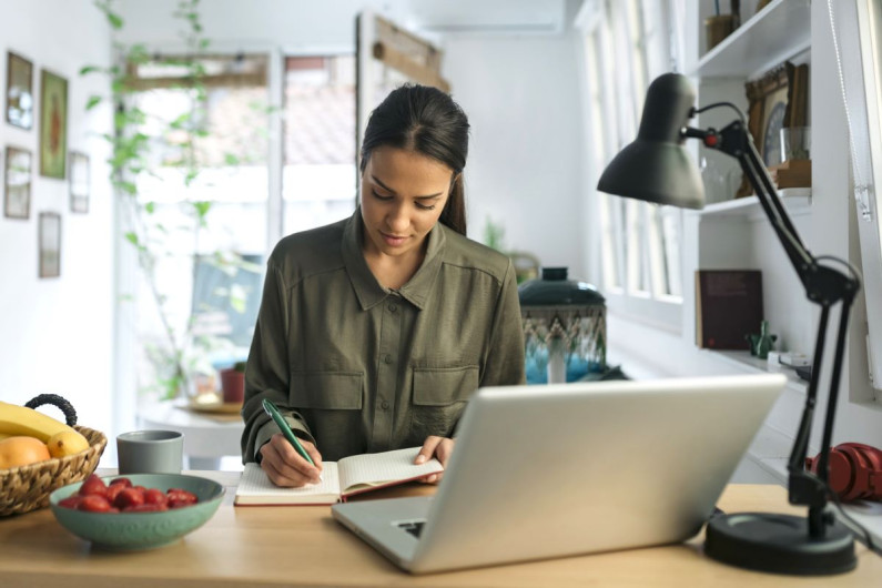 Woman writing notes on a table at home 