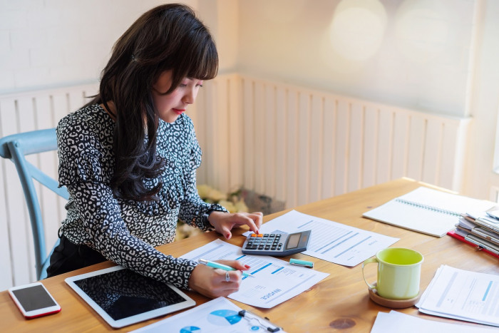 A female accounts officer sits at a desk calculating a customer's invoice