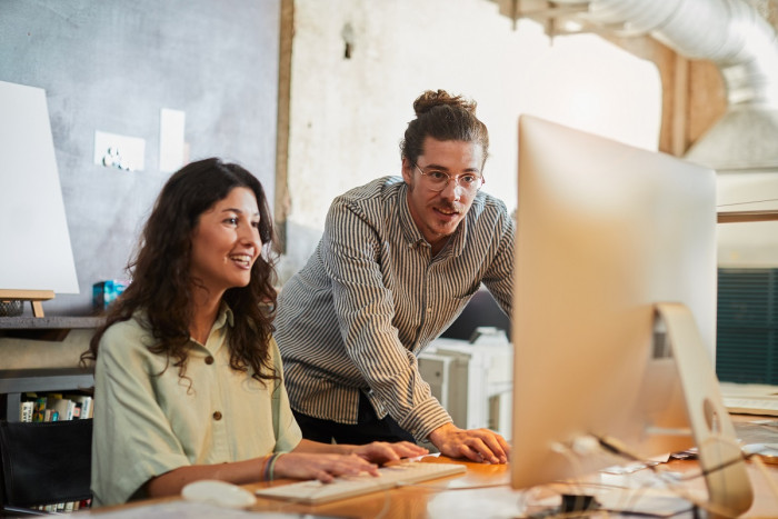 Two advertising specialists look at work on a computer