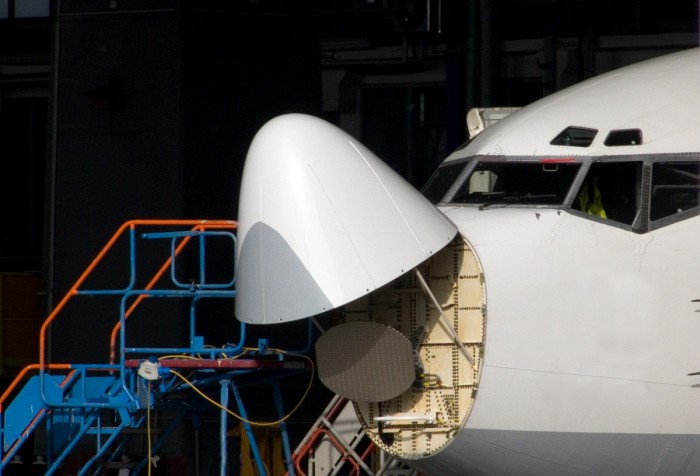 An aeroplane with its nose cone open and a ladder beside it, in a hangar