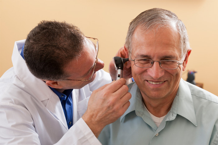 An audiologist inspecting a patient's ear canal