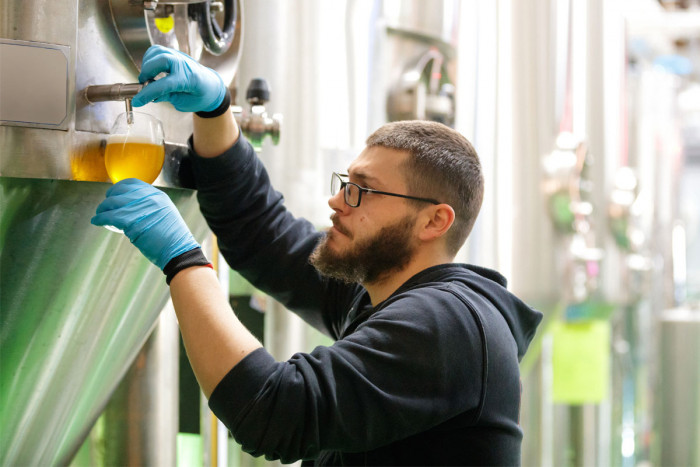 A brewer testing his brew during fermentation