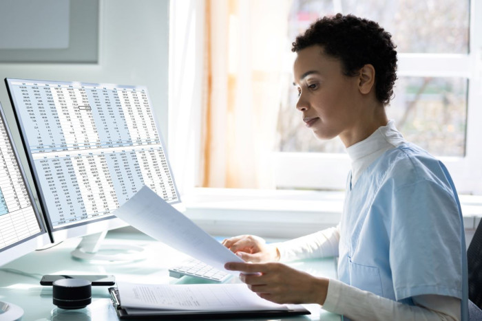 A woman sits at a computer - the screen is full of codes 