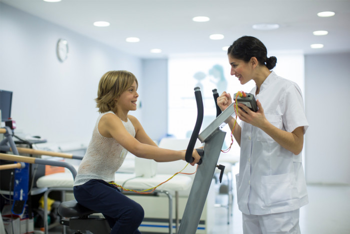 A specialist cardiac physiologist conducts a stress test on a patient using electrodes