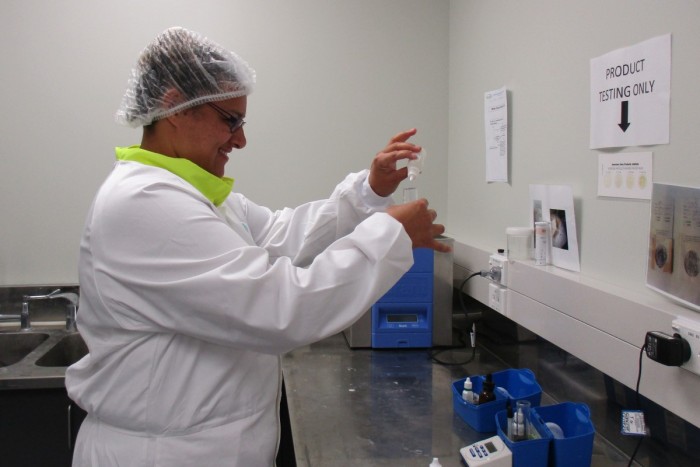 A dairy processing operator standing at a bench testing a milk sample