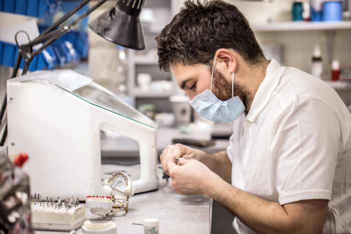 A dental technician working on dentures