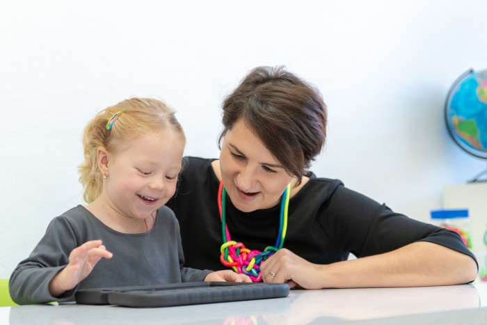 A diversional therapist helping a child with digital exercises on a tablet