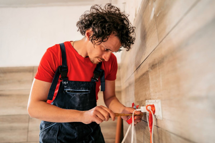 An electrician working on a plug on a wall in a new house 