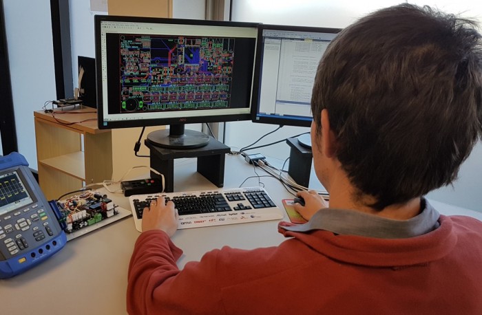Electronics engineer looking at a circuit board on a computer 