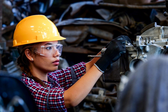 An engineering machinist in protective clothing operates a machine in an engineering workshop