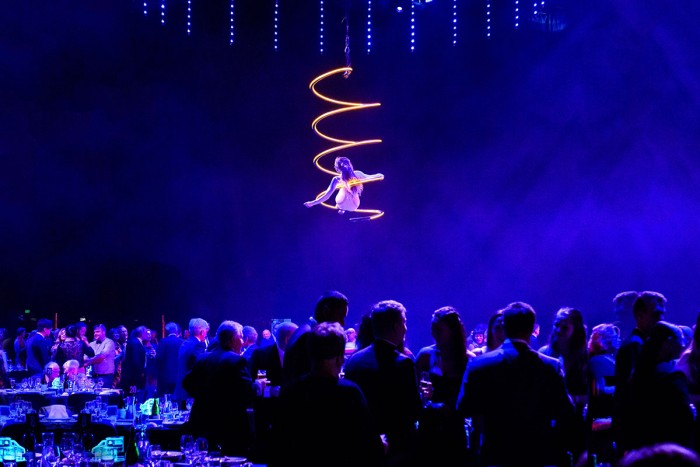 An acrobat performs above a crowd at a corporate event