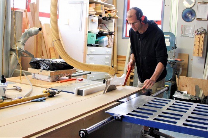 Nick Taylor uses an electric saw to cut a long piece of wood