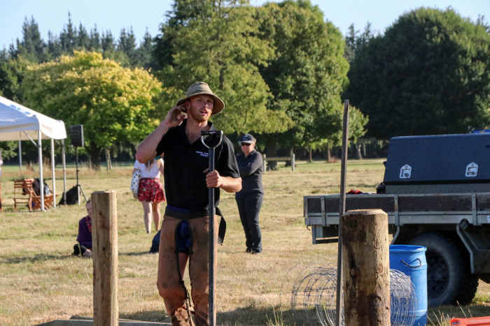 A rural fencer putting posts in the ground