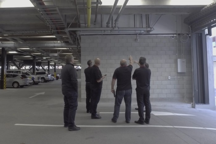 Fire engineers assess sprinkler systems in the garage of a large building