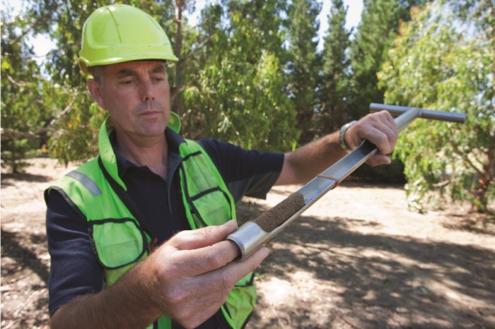 A forestry scientist using a soil sampler