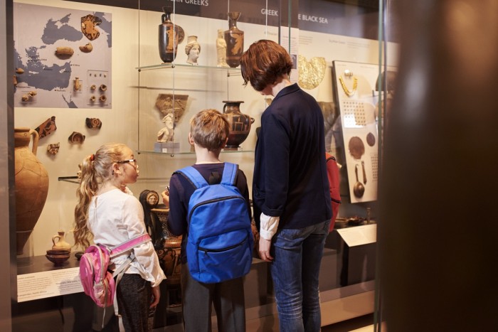 Two children and a woman looking in a display case in a museum
