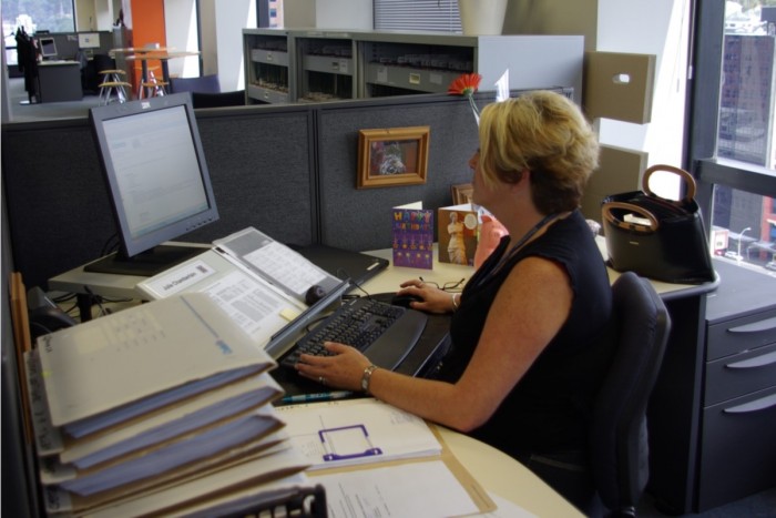 Julie Chamberlain sitting at her computer with a pile of files next to her