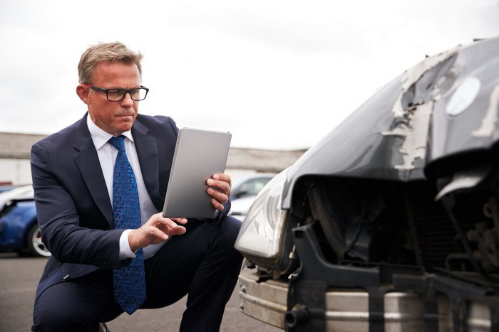 An insurance loss adjuster assesses damage to a vehicle