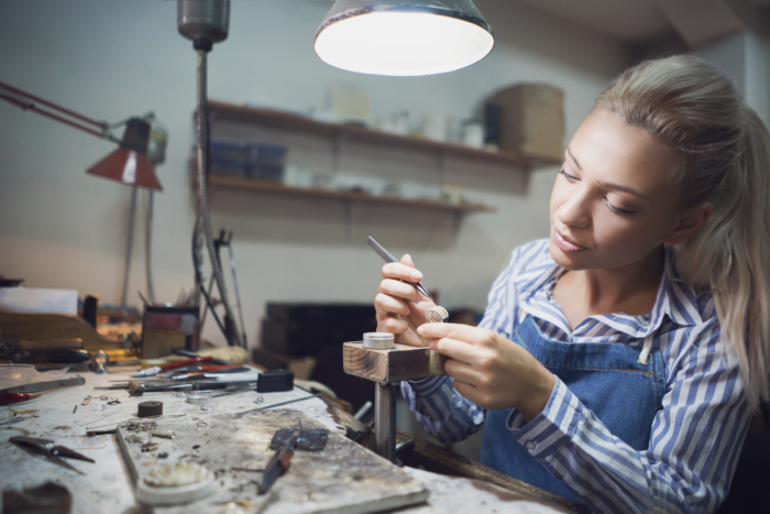 Jeweller seated at a workbench finishing a ring 