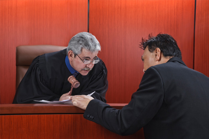 A male judge speaking with a defence lawyer in court