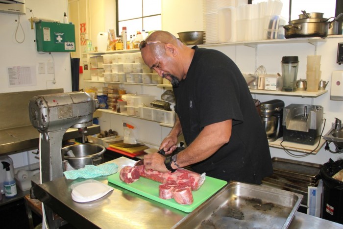 Soul Sosaia slices meat in a kitchen