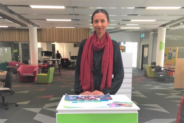 Sana Saleem standing at an information desk in an academic library