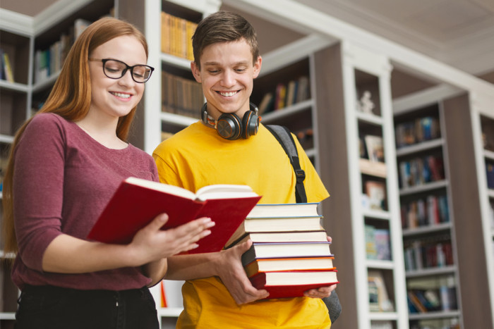 A female library assistant helping a male university learner to find study resources