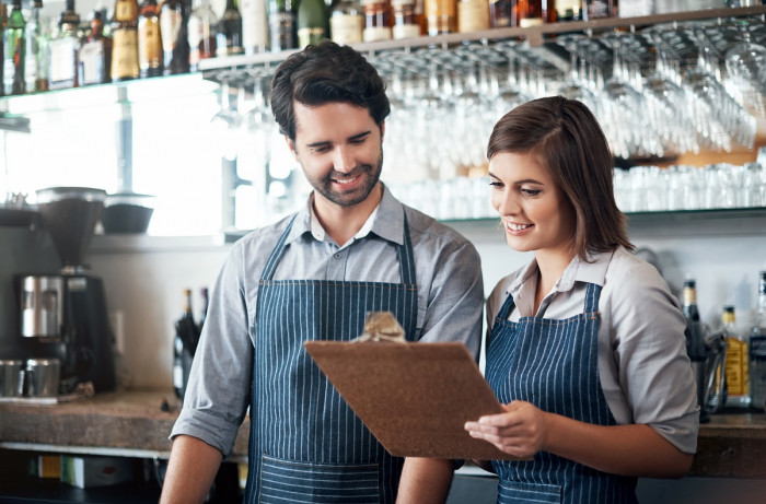 A maitre d'hotel shows a waiter something on a clipboard