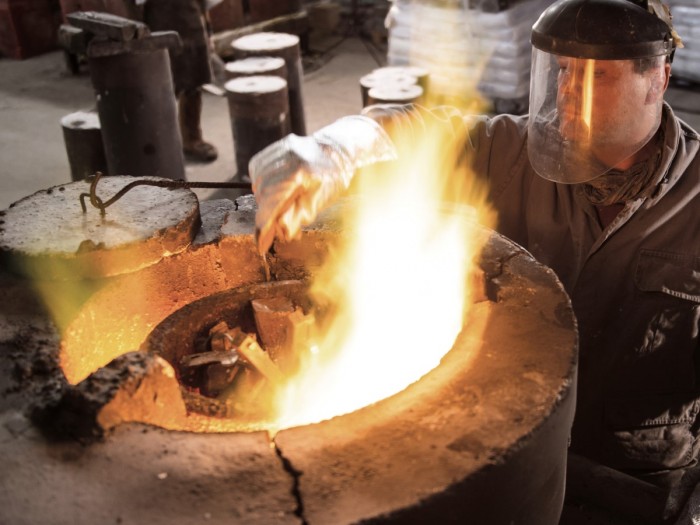 A metal worker melting metal over a hot flame 