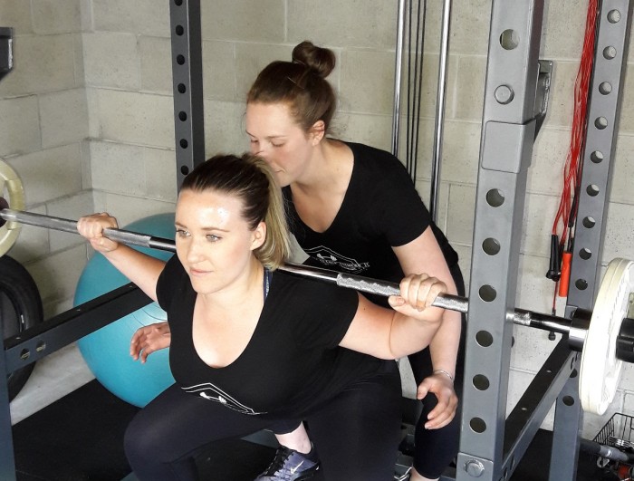 Personal trainer Libby Searle helping a client lift a weight