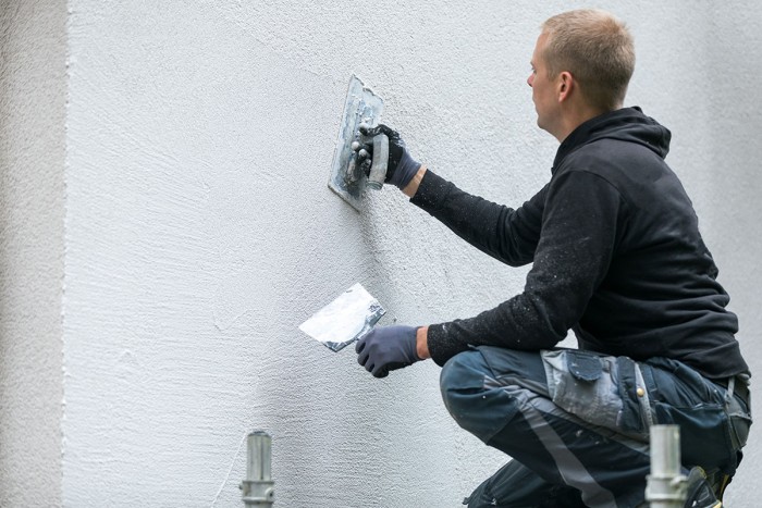 An exterior plasterer applies a decorative finish to a wall