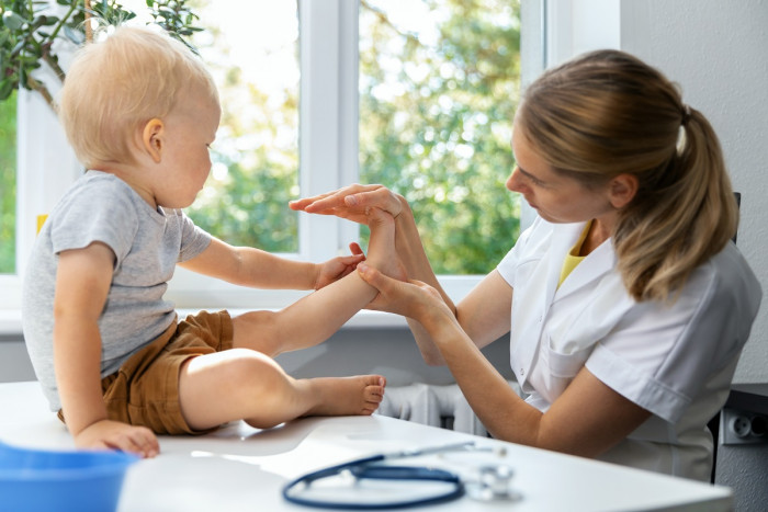 A podiatrist holds a toddler's foot to examine it