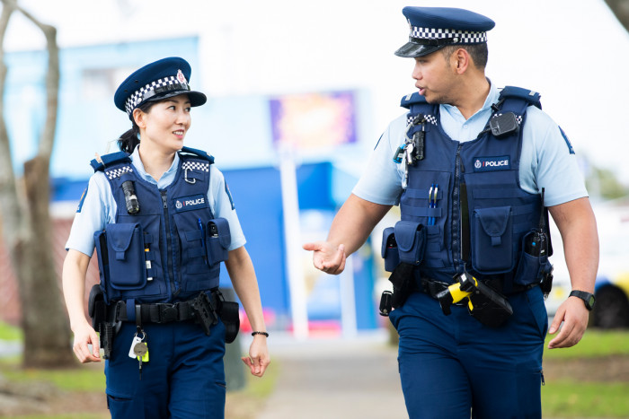 Two police officers talking and walking down a street