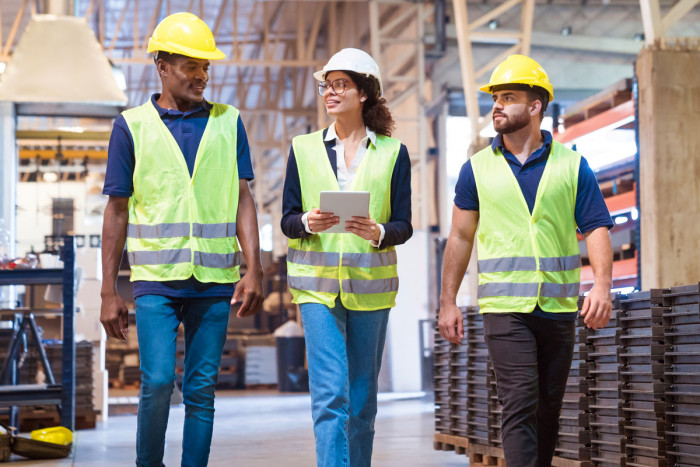 A production manager talking to a quality manager and technical manager at a factory