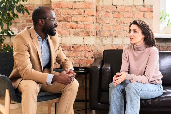 A male psychiatrist listens to a young female patient 