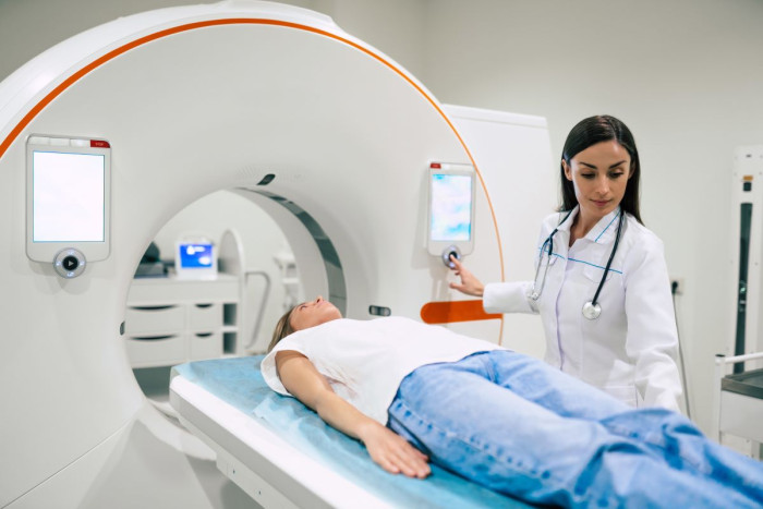 A Radiation oncologist adjusts a dial as a woman lies ready to receive radiation 