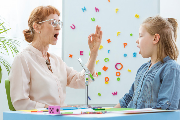 A speech-language therapist teaching a child vocal exercises