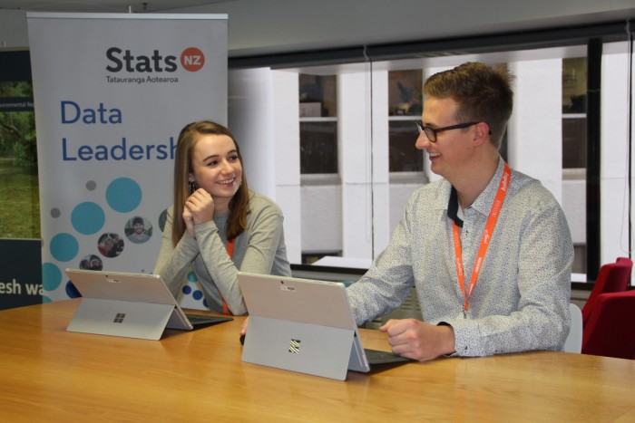 Statisticians with laptops sit at a table discussing a project