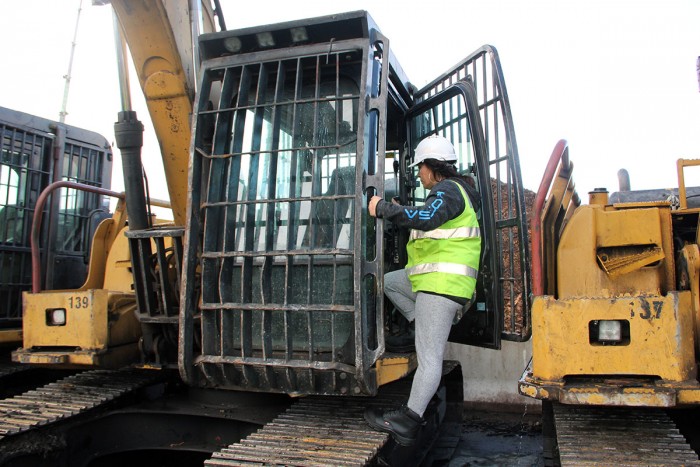 Linda Kingi climbs into the cab of a digger