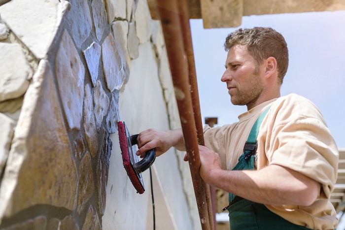 A man sets stone panels into a wall