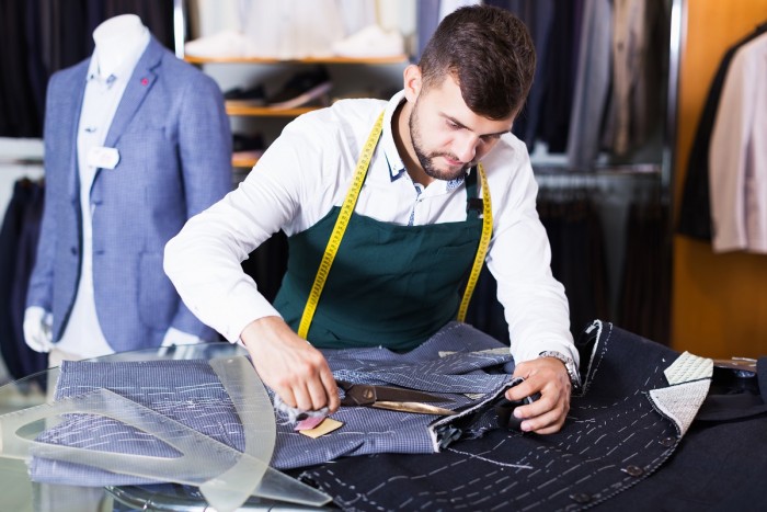 A man is trimming a suit with scissors